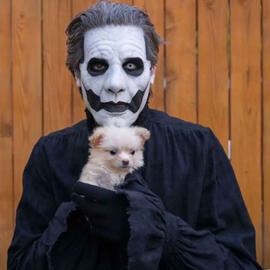 Papa Emeritus from the band Ghost holding a puppy